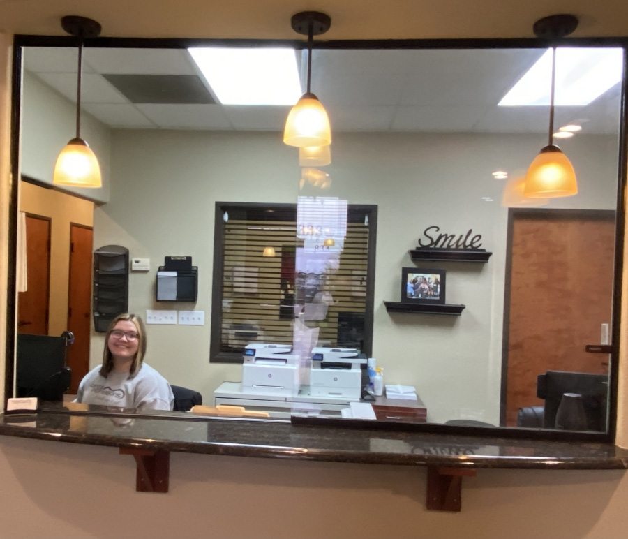 Smiling receptionist at front desk of Dental Expressions
