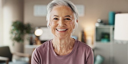 Older woman smiling after receiving dental implants