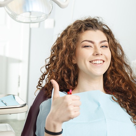 Female dental patient giving thumbs up