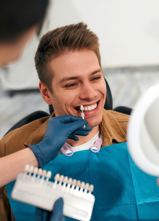 A dentist using a shade guide to determine LUX no-prep veneers in Oklahoma City