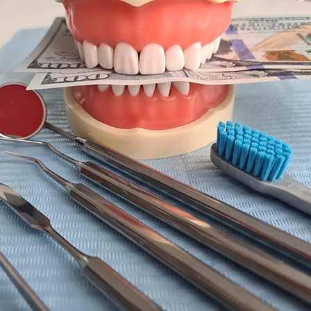 A mouth mold holding money with nearby dental instruments